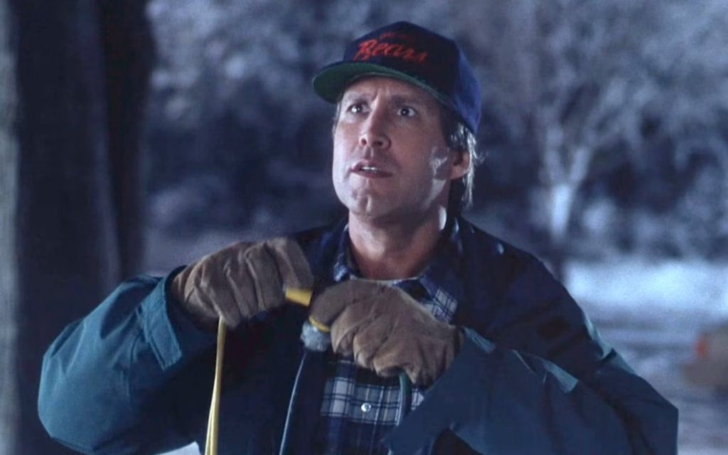 A frustrated Clark Griswold tangled in Christmas lights, holding them up with an exasperated expression from the movie National Lampoon’s Christmas Vacation.