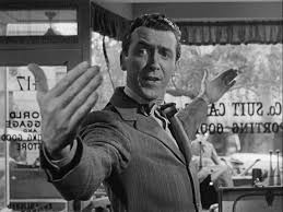 George Bailey from It’s a Wonderful Life joyfully extending his arms in a welcoming gesture inside a small-town storefront.