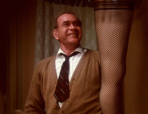Ralphie’s dad, The Old Man Parker, from A Christmas Story grinning proudly while admiring the iconic leg lamp.